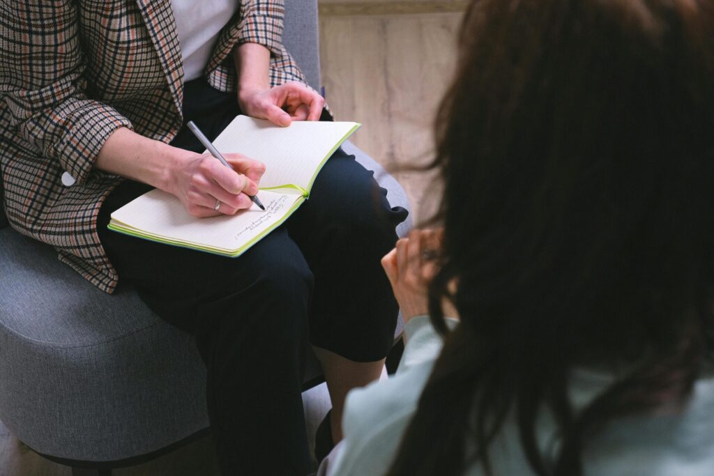 A close-up of a therapy session with a notepad, encapsulating professional dialogue and note-taking.