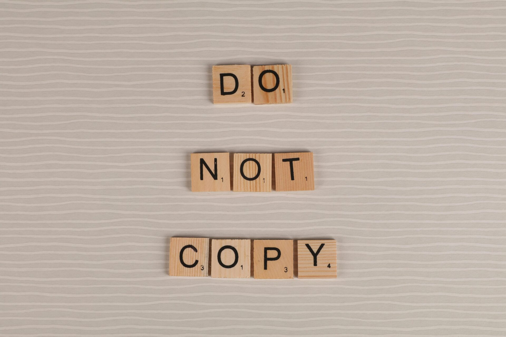 Close-up of wooden tiles spelling 'Do Not Copy' on a textured surface.