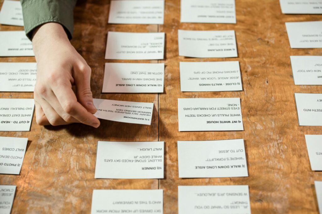 A person arranges cards with various texts on a wooden table, emphasizing focus.